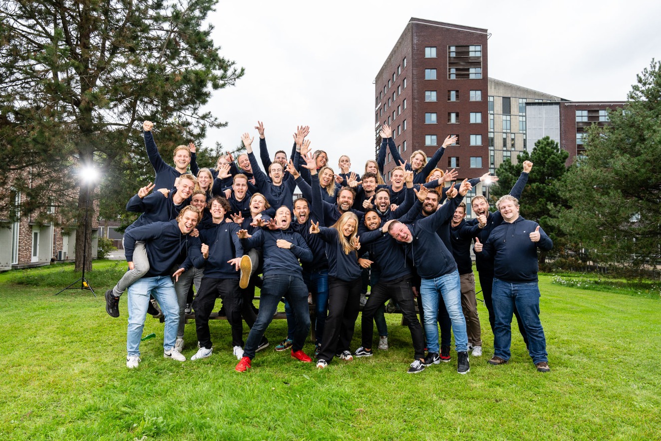 Het supportteam van TriplePro juichend in zwarte shirts op het gras